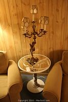 Overall view of lamp on table between chairs against wood panel wall