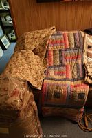 Overall view of two quilts draped on couch showing patchwork designs and decorative cushions