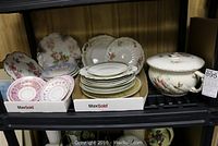 Assorted china plates and covered chamber pot displayed on a shelf