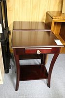 Photo showing the pair of dark stained end tables placed side by side, highlighting the smooth polished tops and curved legs.