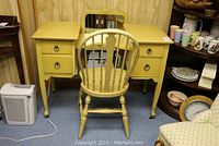 Vanity with four drawers, casters on legs, and hoop back chair in front