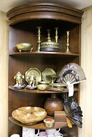 Shelf display showing brass candle sticks, brass bowls, elephant book ends, engraved brass plates, and hand painted fans.