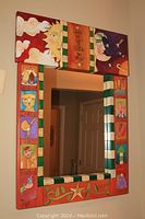 Full front view of mirror showing colorful carved frame and mirror opening