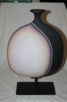 Front angled view of ceramic statue showing color gradient and metal base.