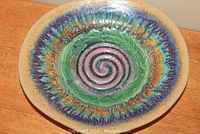 Top view of the colorful hand crafted stoneware bowl showing spiral swirl pattern and textured rim.