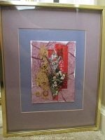 Framed mixed media paper artwork with pink and purple mats, gold frame, featuring red strips with Asian script, green origami floral element, gold wire and beige textured paper elements.