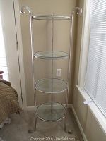 Full view of the tall curio shelf with four glass shelves and antiqued silver metal frame.
