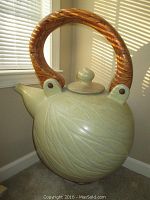 Frontal side view of the large stoneware pot showcasing the carved leaf pattern and wooden handle.