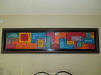 Front view of one long rectangular framed mixed media abstract artwork with geometric colorful shapes in red, orange, teal, and blue.