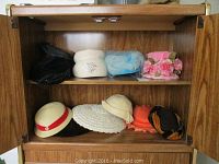 Full view of eight assorted vintage ladies hats in a cabinet shelf, showing various styles and colors