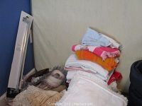 Multiple towels and blankets folded and stacked on a chair with doilies at the base