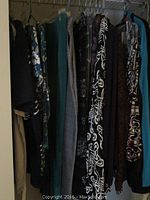 Closet with various women's clothing hanging, showing different patterns and colors, size range likely 14-16.