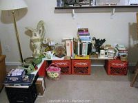 Overall view of collection showing cookbooks, decorative items, and games set on crates and floor
