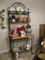 Front view of green metal kitchen shelving unit filled with various plates, baskets, and kitchen decor items.