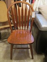 Front view of one wooden spindle back chair; shows arched top rail and vertical spindles