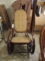 Front view of the wooden rocking chair showing upholstered seat and backrest with button tufts