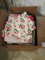 Box with folded tablecloths, floral rose print cloth on top