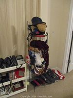 Small black metal shelving unit filled with scarves, hats, and fans in living room environment