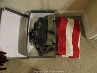Photo of the Ikelite SLR underwater camera housing inside a box with the folded US flag lying next to it on the floor.