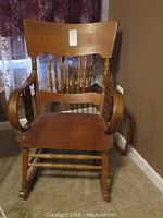 Front view of wooden rocking chair showing wide backrest, spindle details and armrests