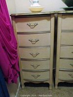 Front view of paired wood chest of drawers with five drawers each, showing decorative handles and worn finish.