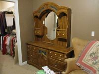 Full view of wood dresser with attached arched mirror featuring an oval reflective surface and small side drawers.