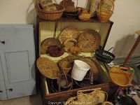 Vintage storage chest open with multiple woven baskets visible inside, showing the inside space and contents.