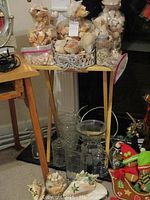 Plastic bags and wicker basket filled with assorted seashells on a wooden table alongside multiple clear glass vases.
