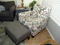 Armchair and ottoman set placed in a corner near a window, showing whole pieces.