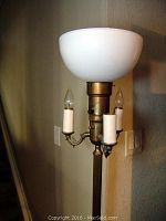Close-up of the lamp's upper light bulb holders with opal glass bowl-shaped shade above, metal arms holding three candle-style sockets with faux candle sleeves.