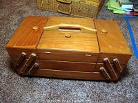 Closed wood sewing box with handle on top and wooden knobs on compartments.