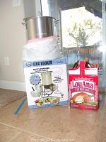 King Kooker deep fryer kit box, large stainless steel pot on top sealed in plastic, LouAna peanut oil container beside it.