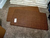 Two brown gel floor mats laid on carpet showing top woven texture side.