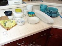 Overview of mixed dinnerware on countertop, showing plates, bowls, pitchers, and serving platter.