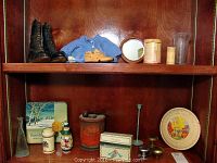 Full lot on shelf with boots, shoe, blue sweater, tins, mirror, glass vases, doorknobs, and candlestick