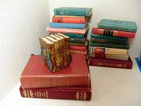 Photo showing the stacked 22 vintage books including a miniature set, with variegated colors and visible spine texts