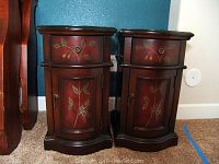 Front view of two cherry wood night stands with floral painted designs on drawers and doors
