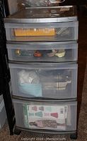 Front view of the plastic storage drawers showing sewing supplies inside