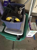 Image showing blue and green plastic bins stacked containing painting and caulking tools along with a box of Poly-Blend grout.