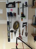 Full view of pegboard with assorted hand tools including screwdrivers, levels, saws, hammer, mallet, scissors