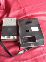 Both the main cassette player unit and the attached remote speaker unit with strap, shown on a red surface.