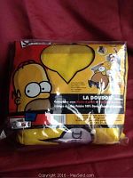 Photo showing new packaged yellow snuggle blanket with Homer Simpson design and description.