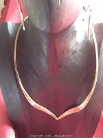V-shaped sterling silver necklace with gold wash tones displayed on black mannequin bust, showing front view of necklace.