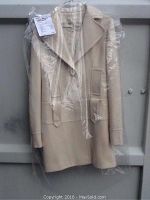 Full view of cream colored Guess women's coat dress jacket in plastic cover showcasing overall design and length.