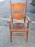 Full view of pressed back wooden armchair with leather seat