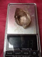 Smoky quartz crystal placed on a digital scale showing weight 21.3 grams.