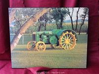 Photo of a mounted picture featuring a green John Deere antique tractor on a grass field with yellow wheels and a background of trees and cornfield