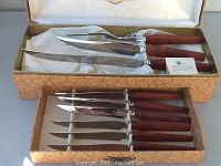 Carving set showing carving knife, fork, and six steak knives with wooden handles in original box.