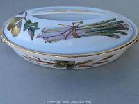 Closed oval ovenproof dish with lid showing asparagus and pears decoration on top, with wheat sheaves around side and gold trim around edges.