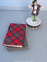 Porcelain Scottish bagpiper figurine music box alongside two tartan pattern covered books